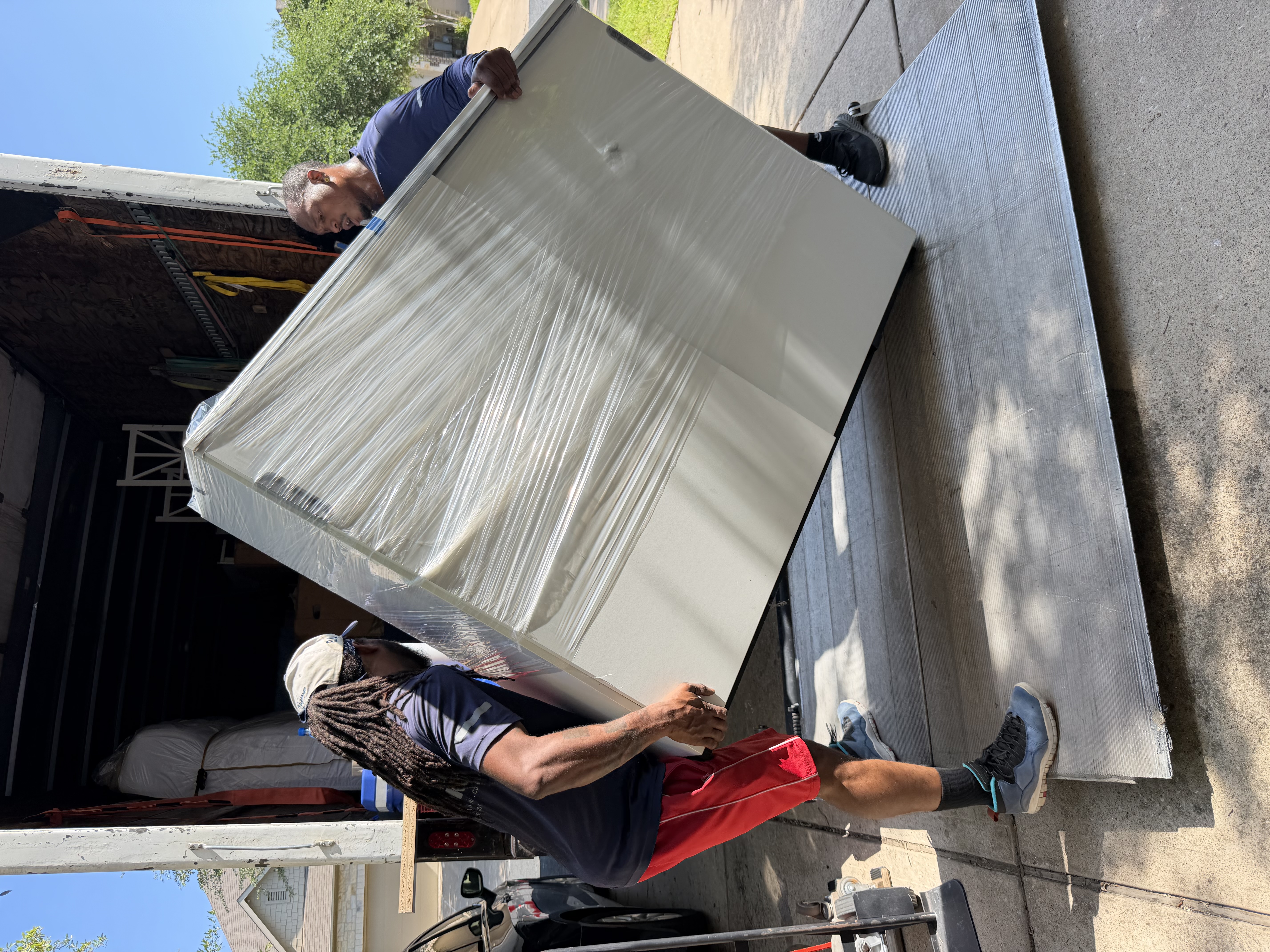 Playhouse Moving crew unloading a large appliance from the moving truck