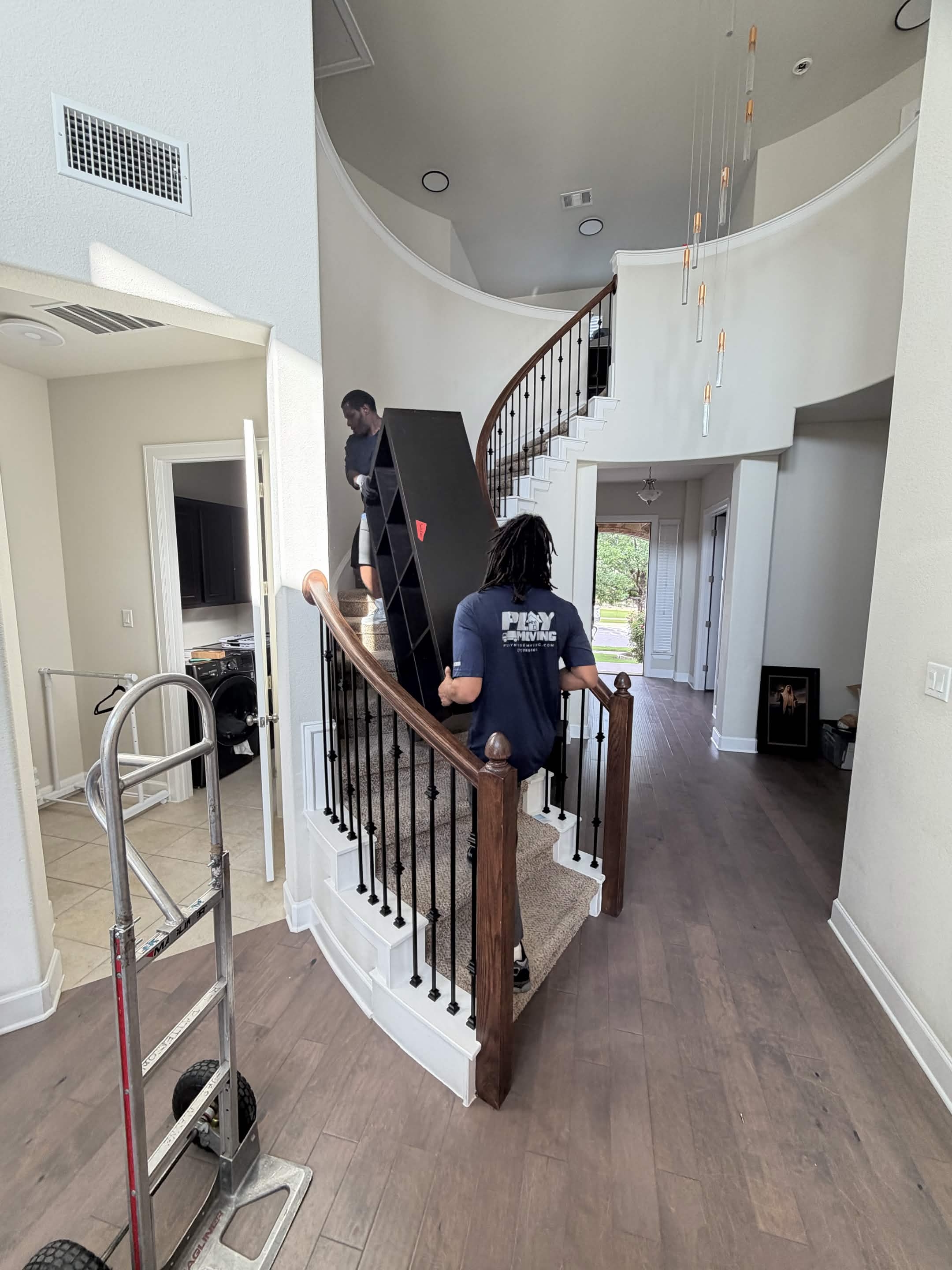 Playhouse Moving crew carrying furniture down a staircase in an Austin home
